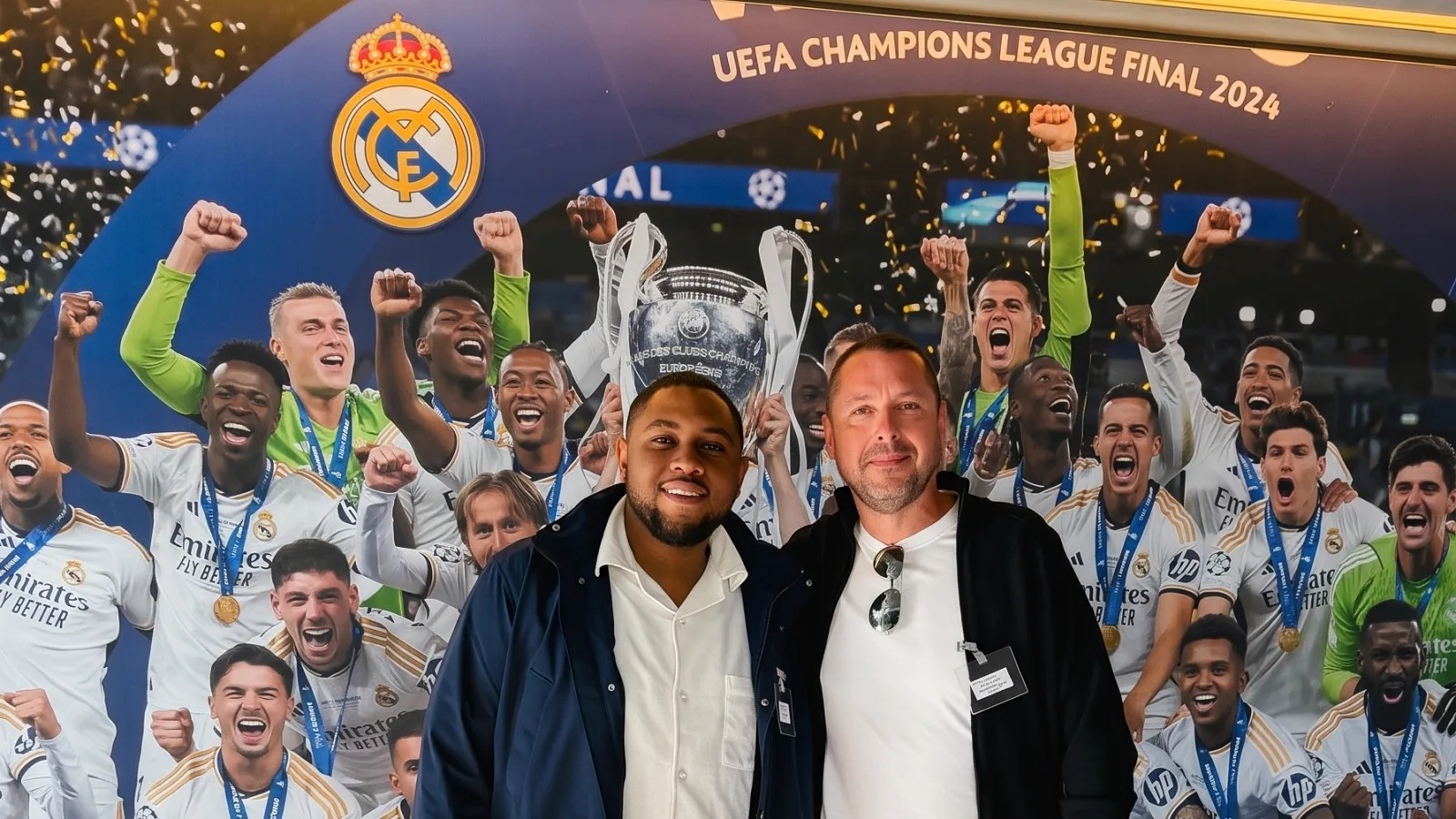 Le président du Talent de Demain FC avec un représentant du Real Madrid devant la fresque de la finale de Ligue des champions 2024